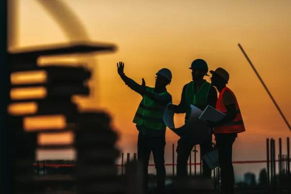 Construction workers evaluating how they can lift heavy loads with the use of a portable gantry. 