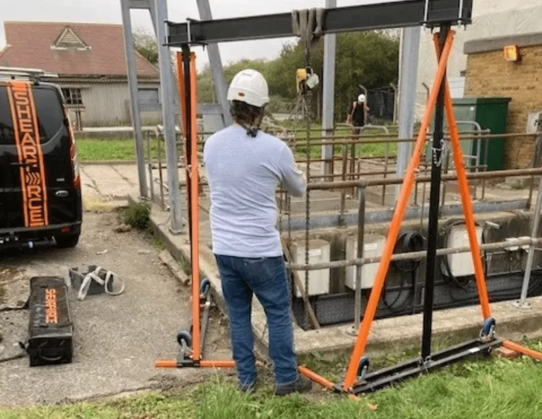 A construction worker exploring the advantages of using an aluminium gantry on a construction site to lift heavy weights.